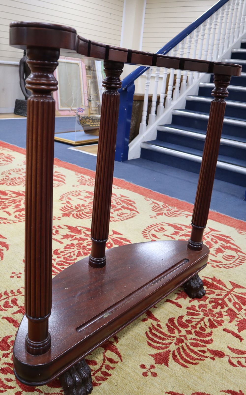 A mahogany sword stand, bow shape with reeded columns, claw feet, 92cm